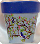 Cherry blossoms and bluebirds painted on terra cotta pot with light blue background,dark blue rim